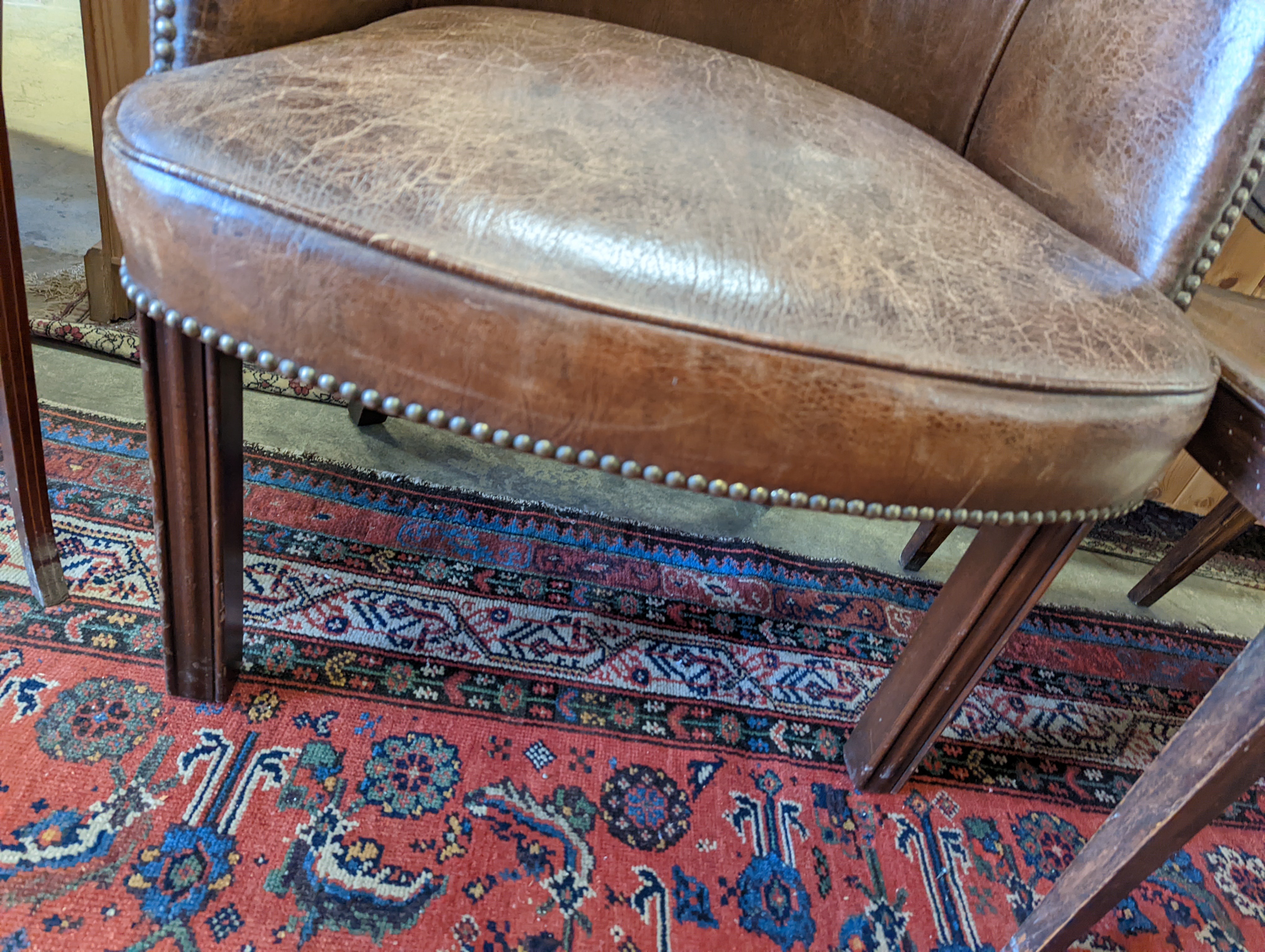 A brown leather upholstered desk chair, a mahogany hall chair and two upholstered armchairs